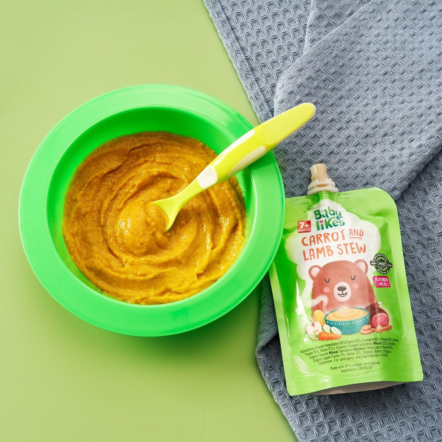 Bowl of Baby Likes Carrot and Lamb Stew served next to its branded baby food pouch, showcasing a wholesome weaning meal